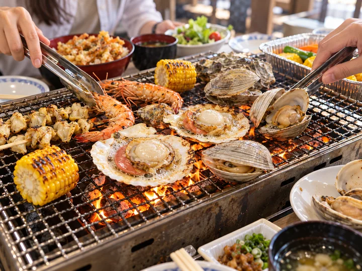 トングで魚介を焼く卓上海鮮バーベキューの写真風のイメージ図
